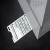 A white card with stitch patterns is partially inserted into a gray sewing machine. Náhled obrázku produktu