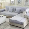 Heller grauer gesteppter Sofabezug auf einem L-förmigen Sofa mit passenden Wurfkissen in einem Wohnzimmer Náhľad obrázku produktu