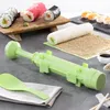 A sushi-making kit is displayed on a countertop, with various sushi rolls and ingredients in the background. Voir les images du produit