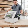 A man is holding a drill and opening a tool case filled with drill bits. Voir les images du produit