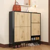 A shoe cabinet with wooden doors and a black frame, displaying shoes on the bottom shelf and floor. Náhled obrázku produktu