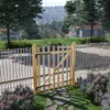 A wooden garden gate in a fence, with houses and trees in the background. Náhľad obrázku produktu