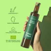 A hand holding a bottle of black cumin seed oil against a light green background with informational icons. Produktbild-Vorschau