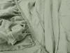 A close-up view of a light green jersey bedsheet, showing the elasticized edge and fabric texture. Anteprima dell’immagine prodotto