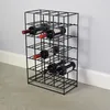 A black metal wine rack filled with wine bottles, standing on a concrete floor against a light gray wall. Produktbild-Vorschau