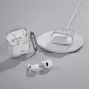 A clear, well-lit studio shot of a transparent protective case for Apple AirPods, along with the AirPods themselves and a wireless charging pad. Produktbild-Vorschau