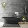 A modern bathroom with a dark gray freestanding bathtub, tiled gray walls, and a small stool with a plant. Náhled obrázku produktu