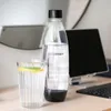 A Sodastream bottle and a glass of water with lemon and mint on a desk. Produktbild-Vorschau