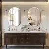 A modern bathroom vanity with two oval mirrors above, featuring sinks and faucets. Voir les images du produit