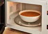 A bowl of soup is being heated in a microwave. Produktbild-Vorschau