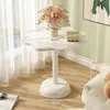 A white side table with a floral arrangement and decorative items, placed near a window with sheer curtains. Produktbild-Vorschau