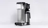 A silver and black filter coffee machine with a thermos carafe, photographed against a white background. Produktbild-Vorschau