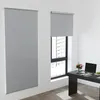 A room with two roller blinds on a wall, one large and one smaller over a window. A desk with a laptop and flowers is visible. Produktbild-Vorschau