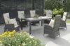 An outdoor patio set with a table and chairs, featuring cushions with an olive pattern, surrounded by plants and flowers. Produktbild-Vorschau