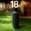 A black outdoor speaker sits on green grass with a blurred background of trees and foliage. A graphic overlay indicates 18 hours of battery life. Náhľad obrázku produktu