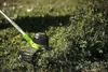 A string trimmer is shown cutting grass and weeds in a yard. Náhled obrázku produktu
