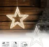 Two illuminated star decorations hanging against a wooden background, with a frosted Christmas tree and ornaments in the background. Podgląd zdjęcia produktu