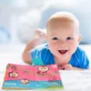 A baby is lying on its stomach and looking at a soft fabric book with colorful illustrations of monkeys. Anteprima dell’immagine prodotto