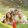 Rote Blasenmaschine mit goldenen Akzenten auf grünem Gras, umgeben von einer Familie und schwebenden Blasen Voir les images du produit