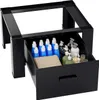 A black steel washing machine stand with an open drawer filled with cleaning supplies. Produktbild-Vorschau