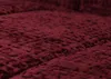 A close-up, angled view of a textured, burgundy fabric, likely upholstery or a blanket, with visible stitching lines creating a quilted pattern. Anteprima dell’immagine prodotto
