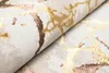 A close-up view of a rolled-up rug with a marble-like pattern in beige, gold, and brown. Voir les images du produit