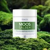 A jar of cream is placed on mossy rocks in a forest setting. Produktbild-Vorschau