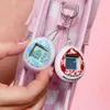 A person's hand holding two Tamagotchi keychains attached to a pink and white checkered bag. Produktbild-Vorschau