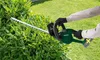 A person is using a cordless hedge trimmer to trim a dense green bush in a garden setting. Produktbild-Vorschau