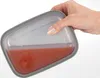 A hand is holding a lunchbox filled with a reddish liquid. Produktbild-Vorschau