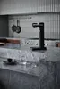 A black Aarke Carbonator 3 sits on a marble countertop in a modern kitchen. Produktbild-Vorschau