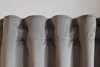 A close-up view of the top edge of gray curtains with pleats. Produktbild-Vorschau