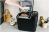 A person is removing a loaf of bread from a bread maker. Podgląd zdjęcia produktu
