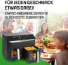 A family is enjoying a meal at a table, with a GOURMETmaxx air fryer prominently displayed in the foreground. Produktbild-Vorschau