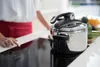 A person is using an induction stove with a pressure cooker on it. Anteprima dell’immagine prodotto