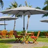 An outdoor seating area with umbrellas, tables, and chairs set up on a lawn overlooking the ocean. Produktbild-Vorschau