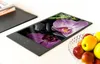 A glass cutting board with an orchid image displayed on a white table, next to a bowl of fruit. Náhľad obrázku produktu