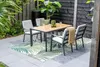 An outdoor dining set with chairs and a table on a patio with a rug and plants. Produktbild-Vorschau