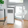 A portable air conditioner unit is set up in a room, with its exhaust hose connected to a window. Produktbild-Vorschau