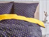 A close-up view of a bed with dark blue and yellow patterned bedding. Náhled obrázku produktu