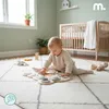 A baby playing with a wooden toy on a rug in a nursery. Produktbild-Vorschau