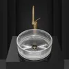 A transparent glass sink with a gold faucet is displayed on a black surface against a black background. Anteprima dell’immagine prodotto
