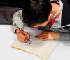A young boy is drawing in a notebook with a red pen. Náhľad obrázku produktu