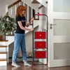 A woman is standing next to a foldable steel ladder in a home hallway. Anteprima dell’immagine prodotto