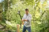 A man is using a sledgehammer to drive a wooden post into the ground in a garden. Voir les images du produit