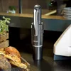A black GRAEF Akkusauger Krümelchef sits on a black counter next to a tray of bread rolls and a white appliance. Podgląd zdjęcia produktu