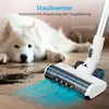 A white cordless vacuum cleaner is shown on a wooden floor, with dirt particles being vacuumed up. A white dog is visible in the background. Anteprima dell’immagine prodotto