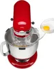 A red KitchenAid stand mixer with a splash guard, with an egg being added to the bowl. Voir les images du produit