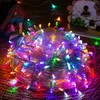 A tangled ball of colorful LED string lights is displayed in front of miniature decorative houses. Náhľad obrázku produktu