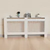 A white radiator cover with a wooden top sits against a light wood-paneled wall, with decorative items on top. Anteprima dell’immagine prodotto